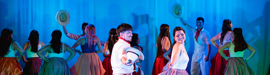 En la imagen aparecen 2 jóvenes danzando el baile típico de Venezuela. Detrás de él y ella aparecen otras jóvenes danzando.