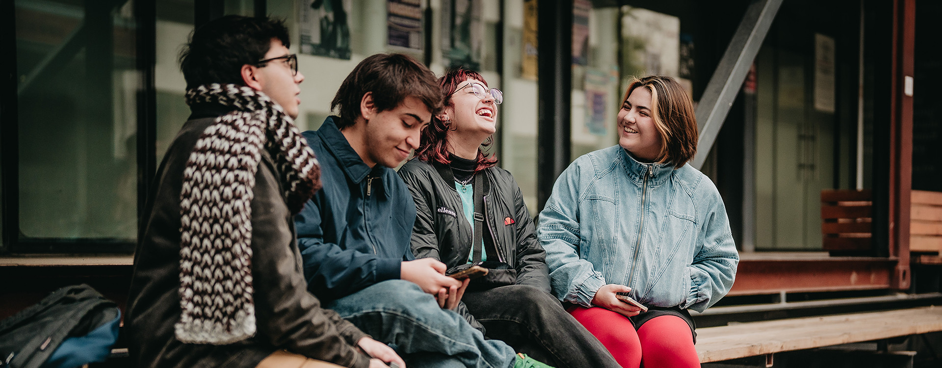 Estudiantes riendo y compartiendo fuera de las salas en el campus universitario